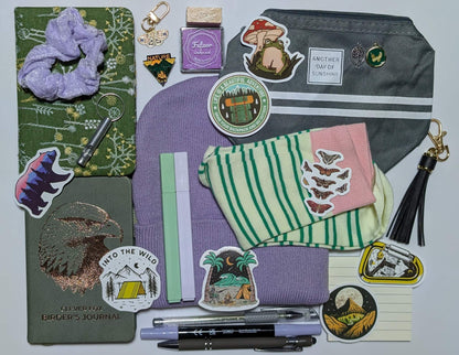 Nature Nerd Legendary Bundle with green floral journal, stickers, ballpoint pen, highlighters, gel pen, markers, keychain, sticky notepad, pin, scrunchie, zippered pouch, and whistle keychain, socks, ink pad, stamp, beanie, charms, birding journal, extra keychain