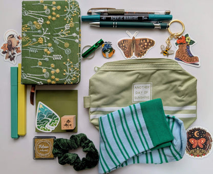 Nature Nerd Deluxe Bundle with green floral journal, stickers, ballpoint pen, highlighters, gel pen, markers, keychain, sticky notepad, pin, scrunchie, zippered pouch, and whistle keychain, socks, ink pad, stamp