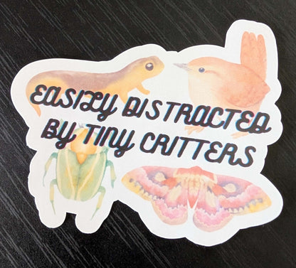 sticker with a moth, newt, beetle, and bird that says easily distracted by tiny critters
