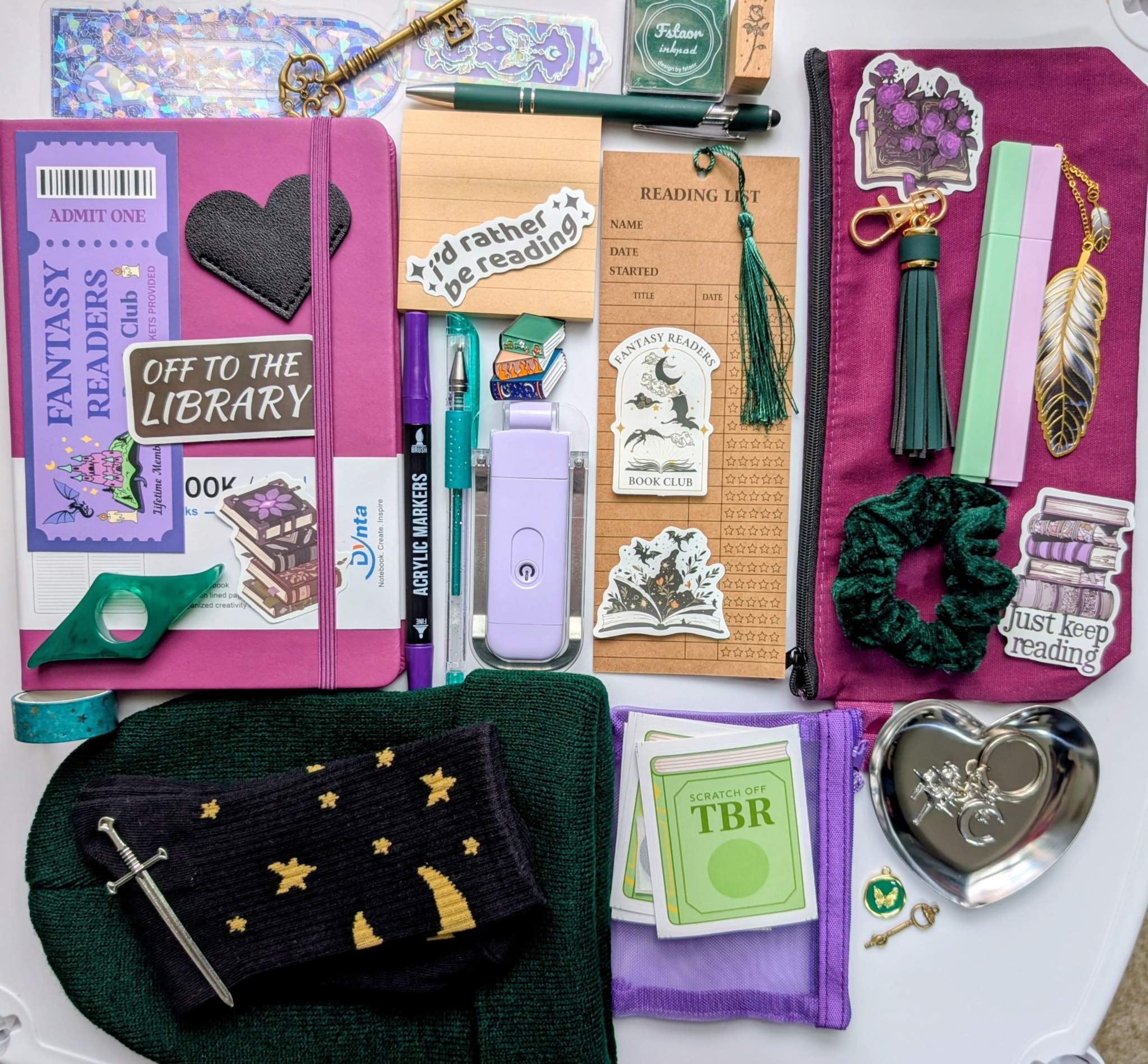 Book nerd legendary bundle with journal, book light, socks, stamp, ink pad, TBR scratchers, stickers, keychain, bookmarks, zippered pouch, highlighters, gel pen, ballpoint pen, marker, page holder, sticky notepad, pin, scrunchie, beanie, trinket dish, keychain, metal feather bookmark, washi tape, key, charms, sword bookmark, mesh pouch Collage