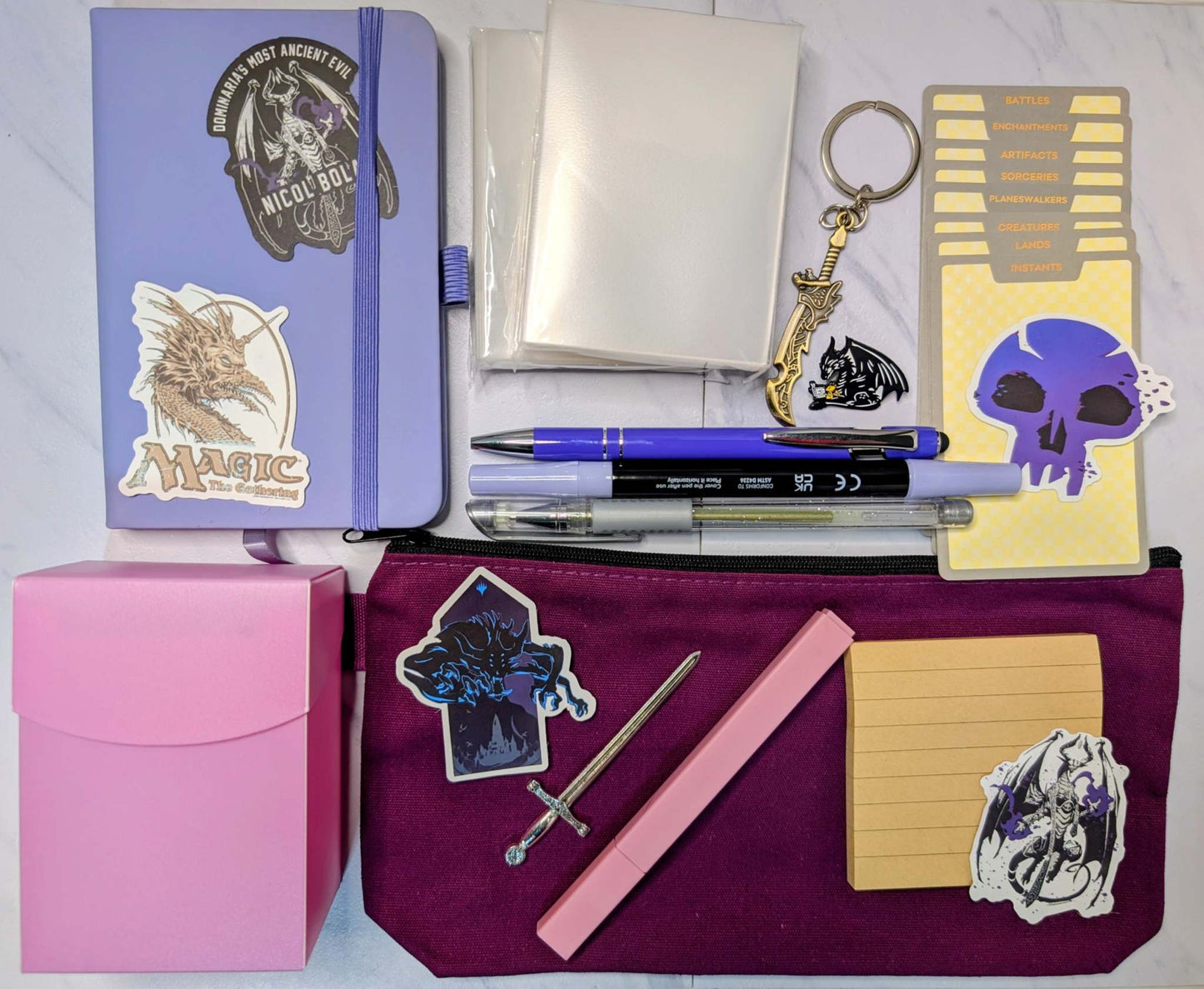 Magic nerd basic bundle wth notebook, ballpoint pen, gel pen, marker, highlighter, sticky notepad, sword keychain, zippered pouch, pin, stickers, sword bookmark, card sleeves, deck dividers, and plastic deck box