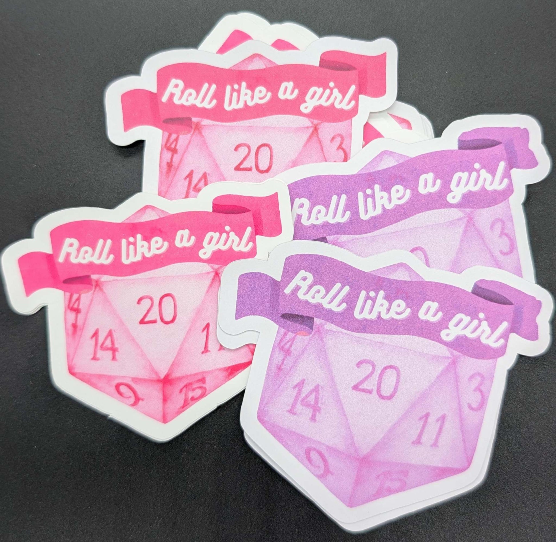 Sticker with D20 dice with a banner reading roll like a girl in pink and purple